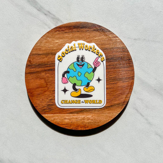Sticker with cartoon character and text 'Social Workers Change the World' on a wooden coaster.