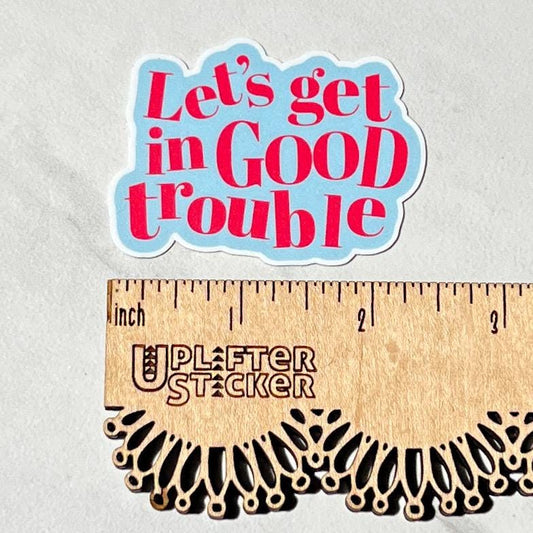Sticker with 'Let's get in Good trouble' text on a gray background, with a ruler for scale.
