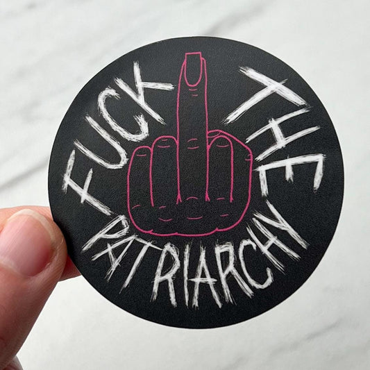 Sticker with middle finger gesture and text 'F*ck the Patriarchy' held by a hand.