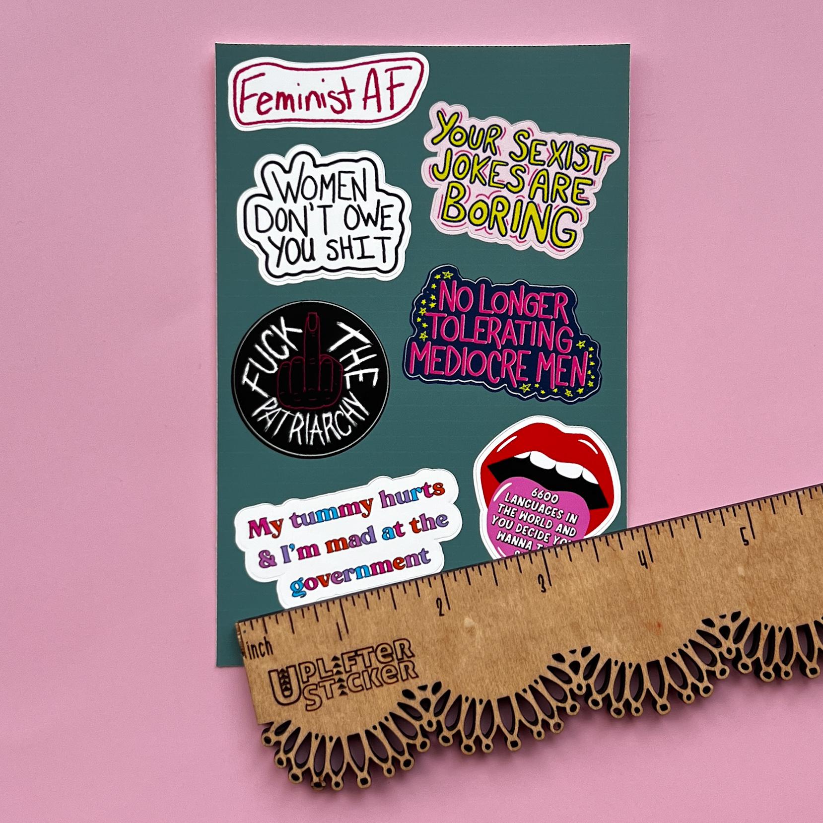 Sticker pack with various statements on a pink background, next to a ruler for size reference.