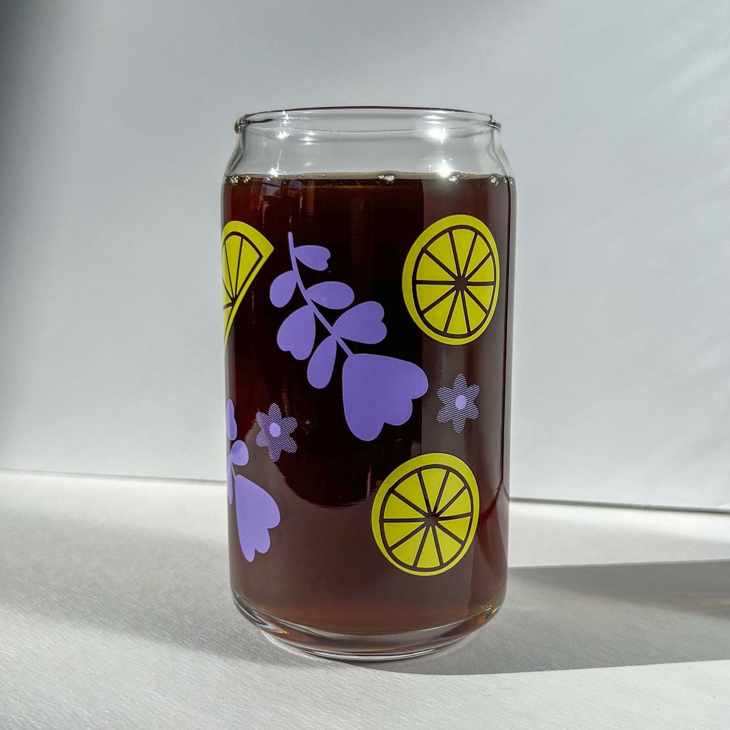 Clear glass can with purple lavender and yellow lemon designs on a white background