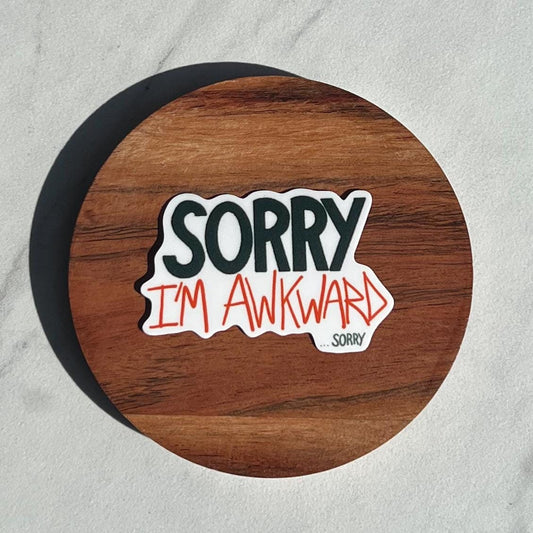 Wooden coaster with a sticker that reads 'Sorry I'm Awkward' on a gray background