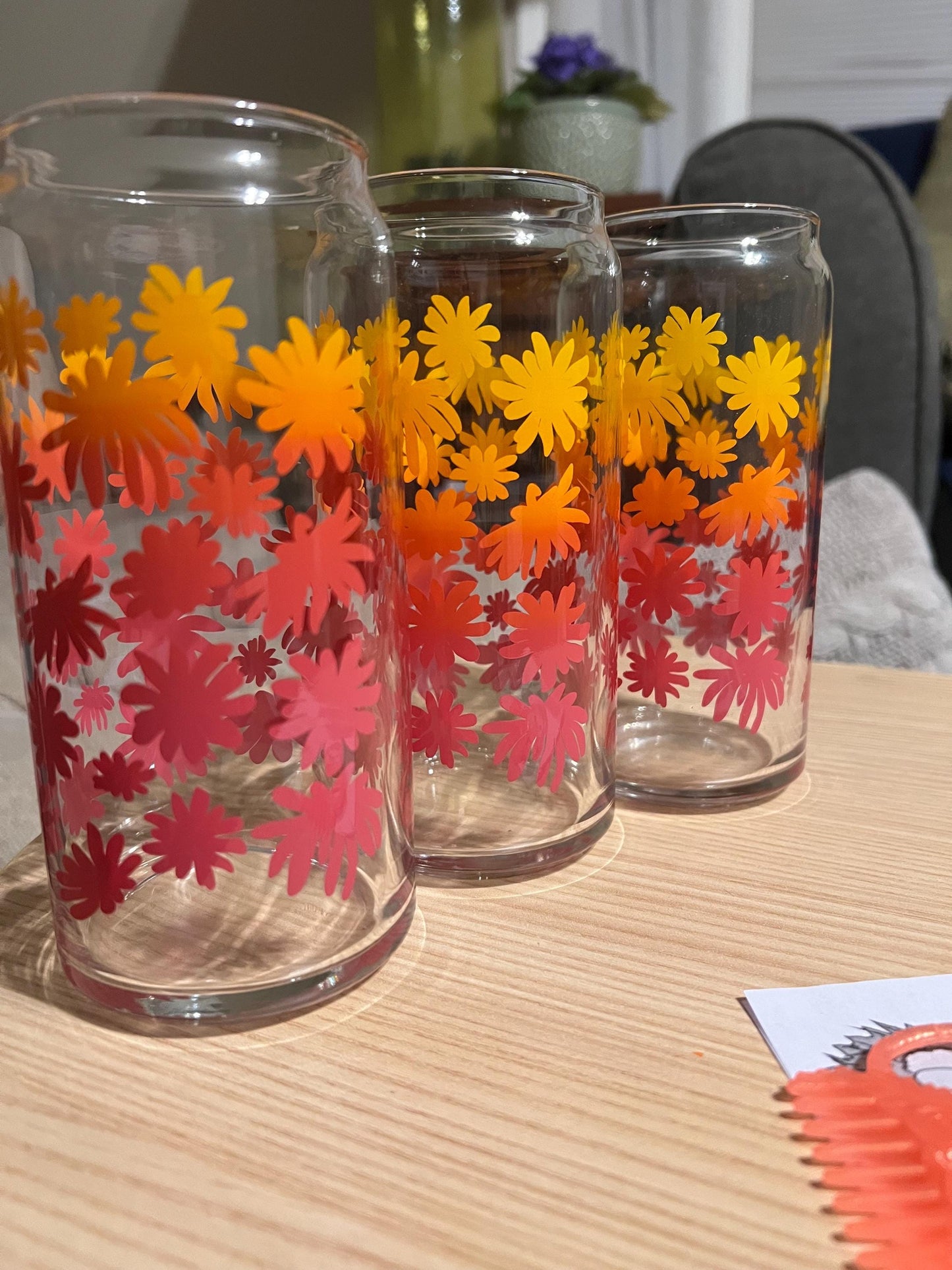 Three glass tumblers with floral designs on a wooden surface.