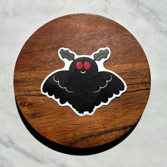 Mothman sticker with red eyes on a wooden circle