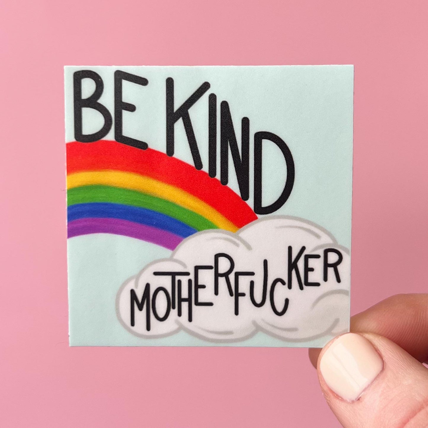 Sticker with rainbow and text 'BE KIND MOTHERFUCKER' held against a pink background
