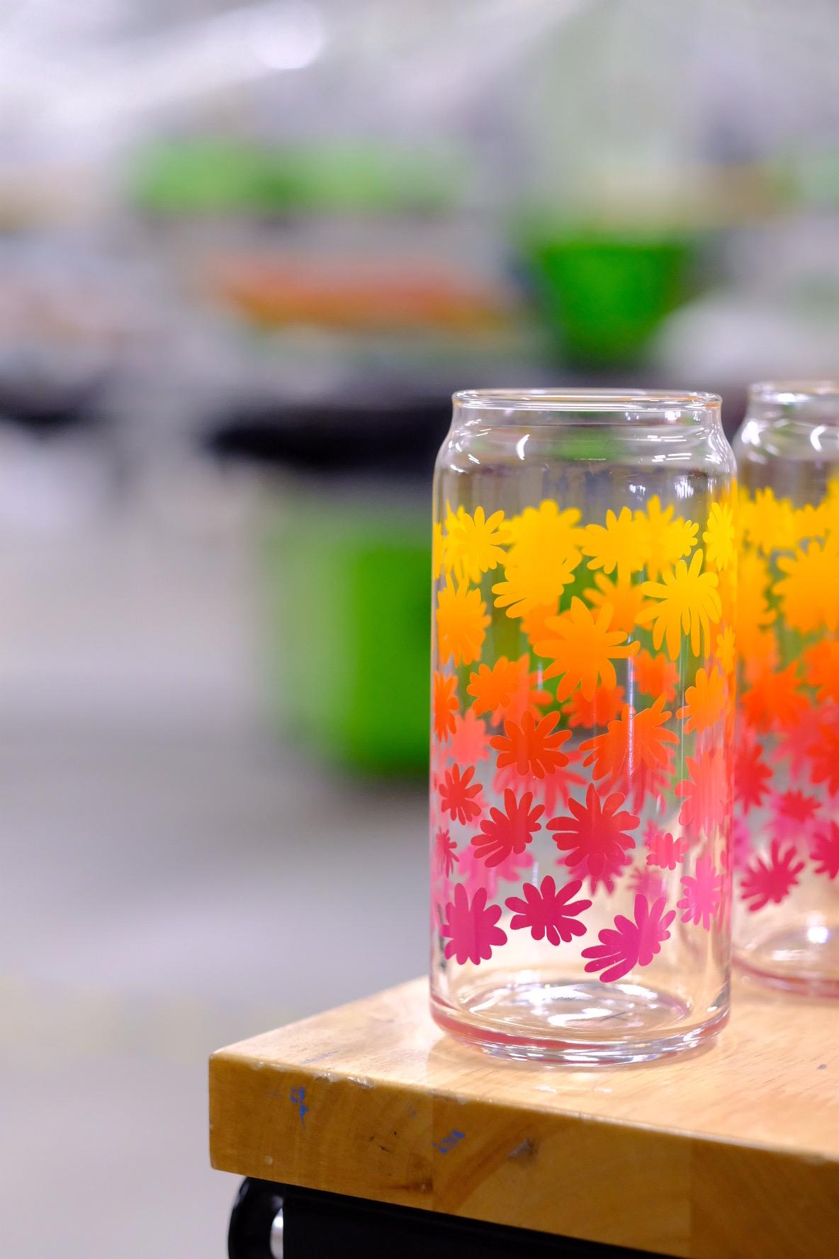 Clear glass jars with colorful floral patterns on a wooden surface.