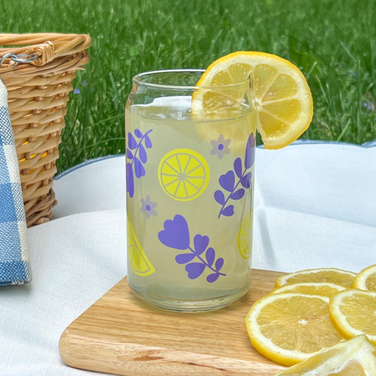 Glass of lemonade with lemon slices in a lemon lavender decorated cup on a wooden board outdoors