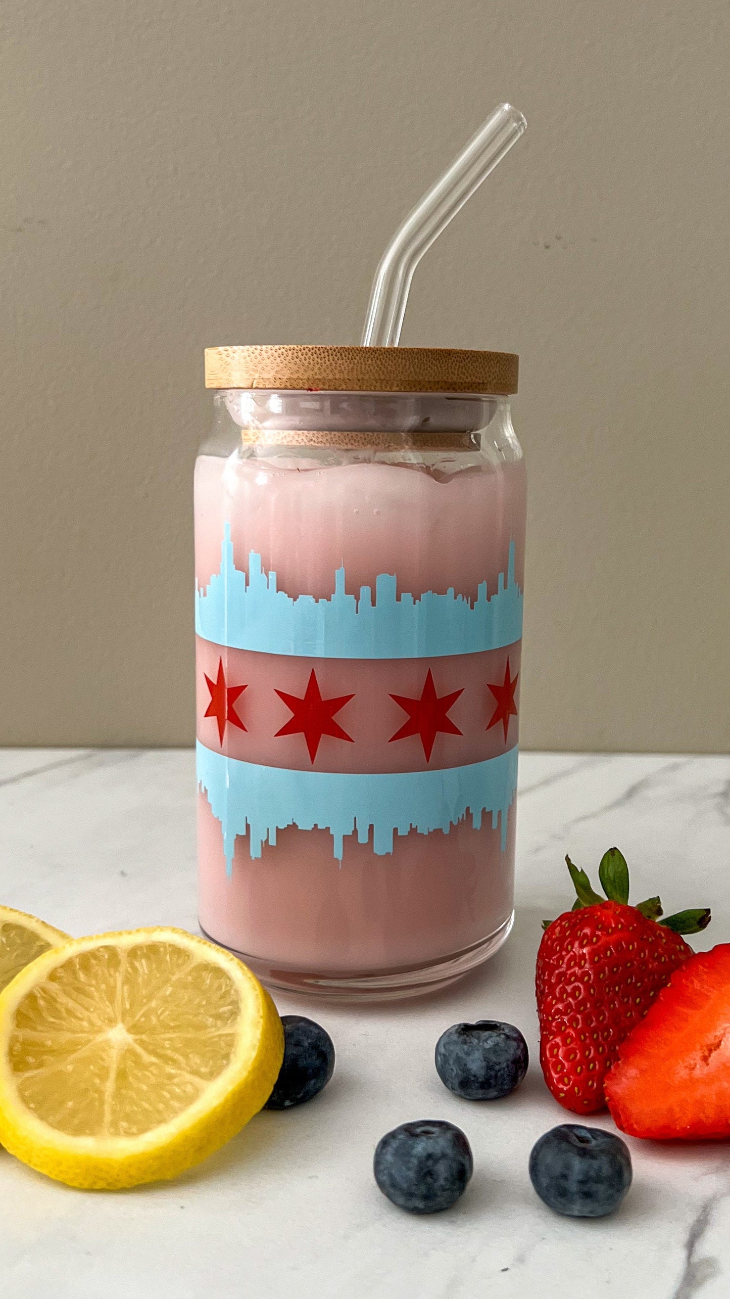 Glass jar with a straw, wooden lid, and Chicago flag with the blue skyline and red star design on a surface with fruits and lemons.