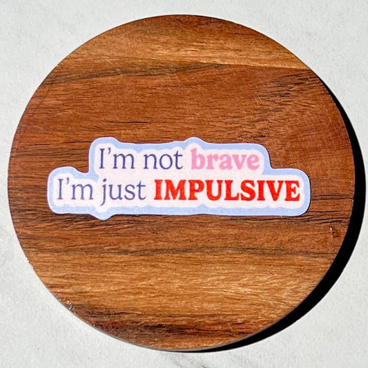Wooden coaster with a colorful sticker reading 'I'm not brave, I'm just IMPULSIVE' on a white background