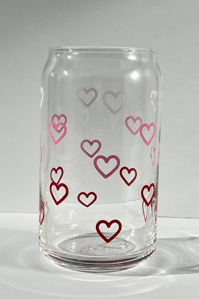 Clear glass tumbler with white, red and pink heart designs on a white background