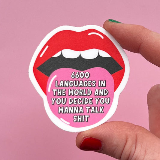Sticker with lips and text held by a hand against a pink background