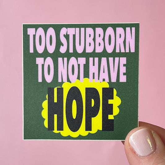 Sticker with 'Too stubborn to not have hope' text on a pink background