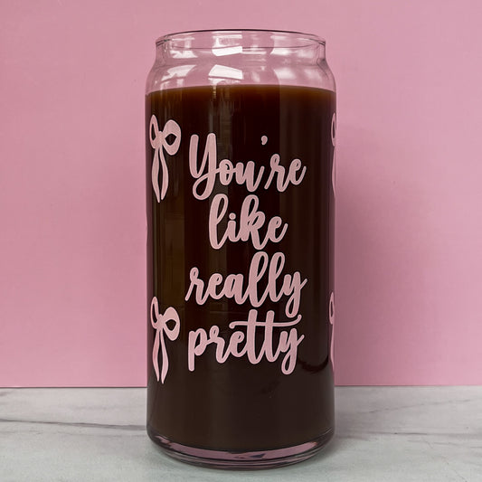 Glass can with pink text that reads "you're like really pretty" with pink bows on a pink background