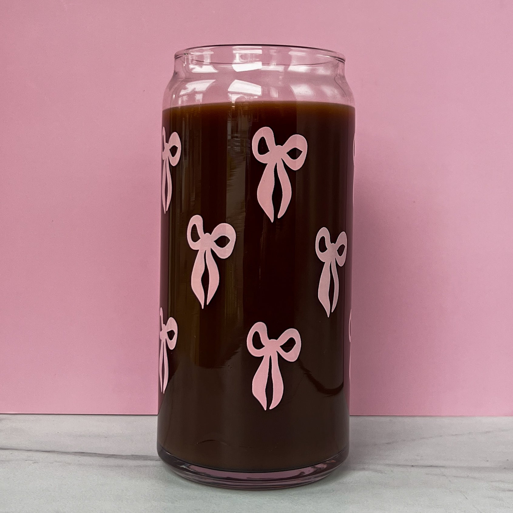 Glass can with pink bows on a pink background