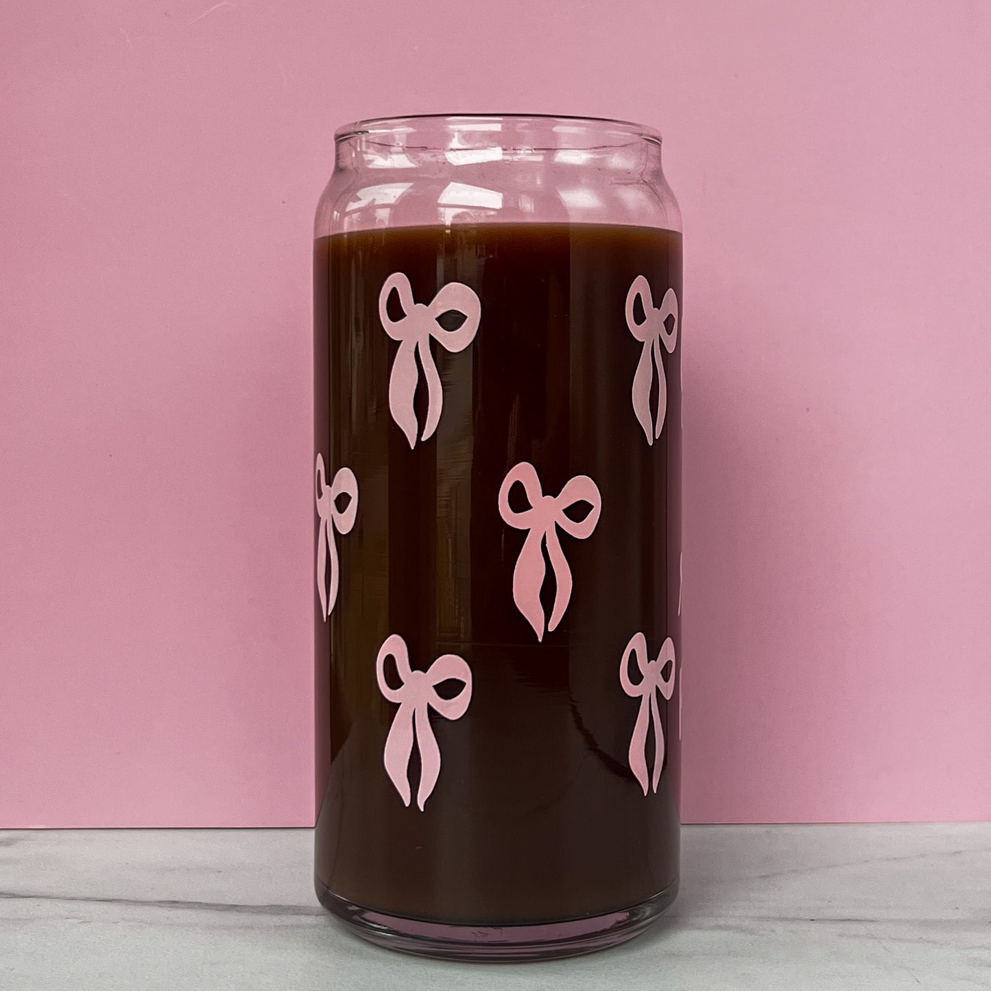 Glass can with pink bows on a pink background
