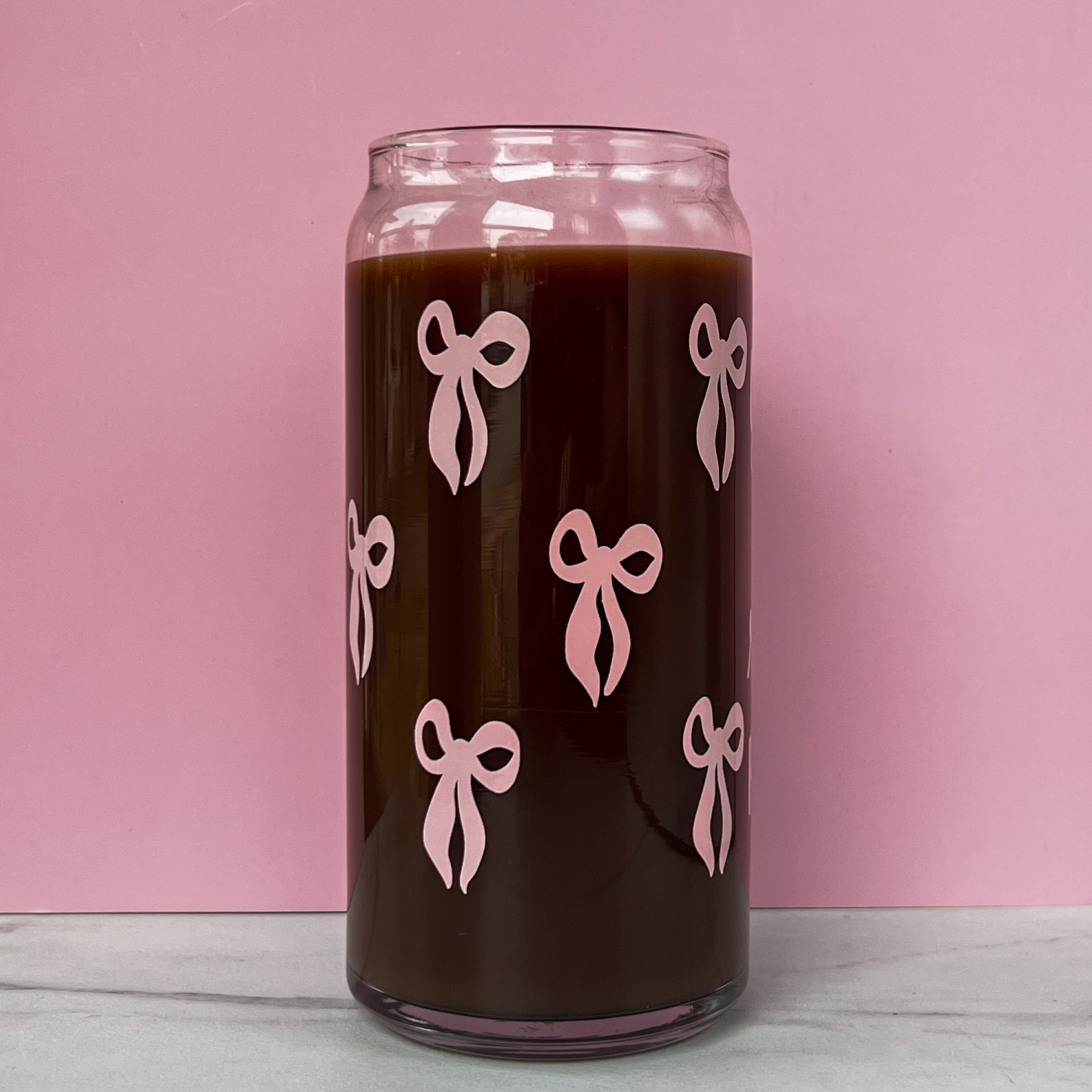 Glass can with pink bows on a pink background