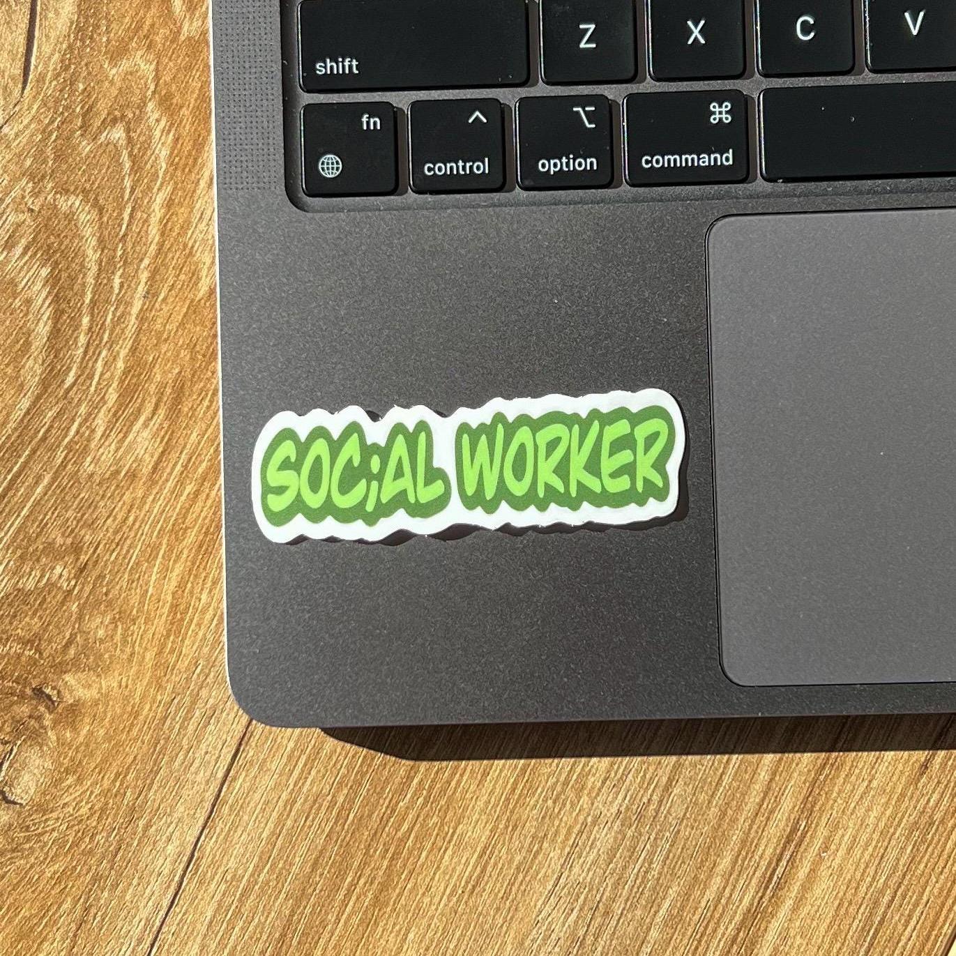 Laptop with a 'SOCIAL WORKER' sticker on a wooden surface