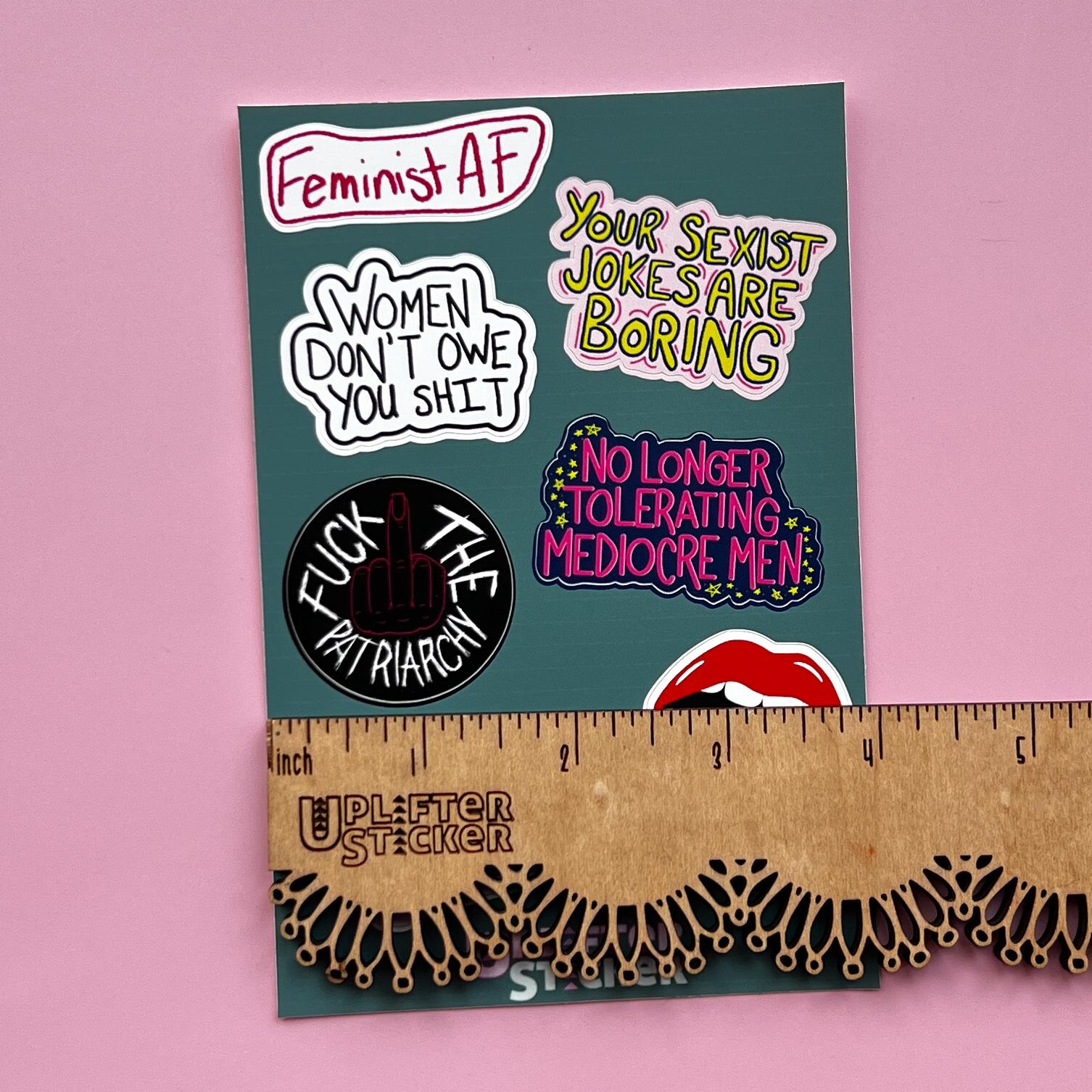 Sticker pack with various statements on a pink background, next to a ruler for size reference.