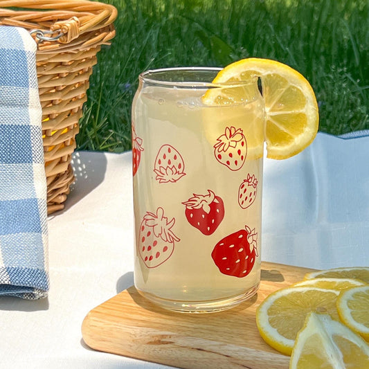 Glass with strawberry design on a wooden coaster outdoors