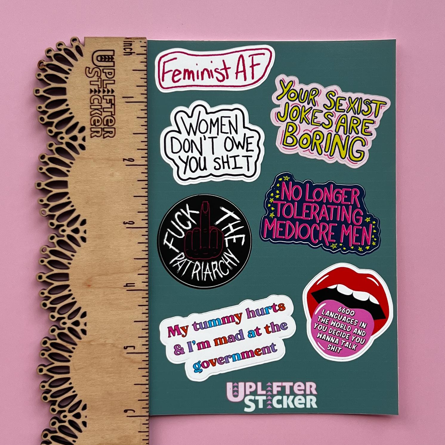 Sticker pack with various statements on a pink background, next to a ruler for size reference.