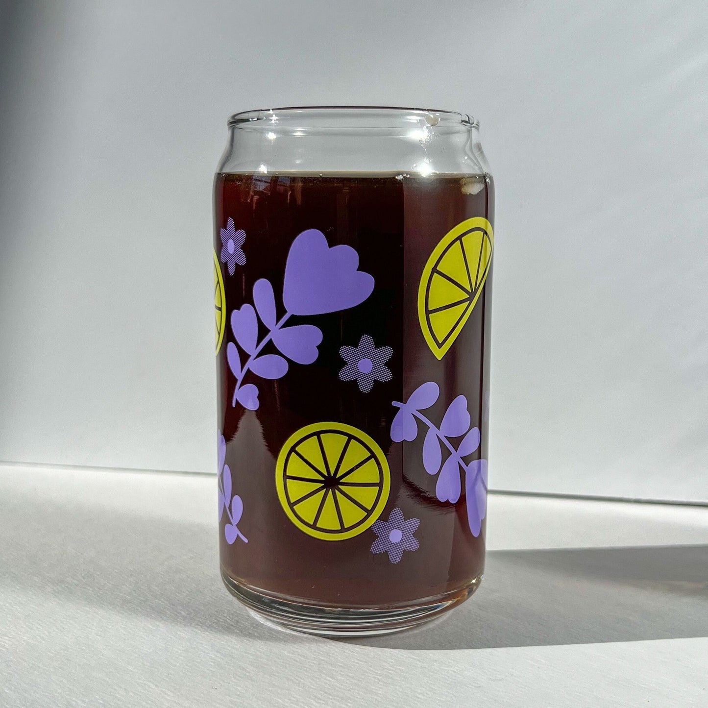Clear glass can with purple lavender and yellow lemon designs on a white background