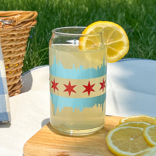 Glass of lemonade with a Chicago flag  with the blue skyline and red star cup design on a wooden table outdoors.
