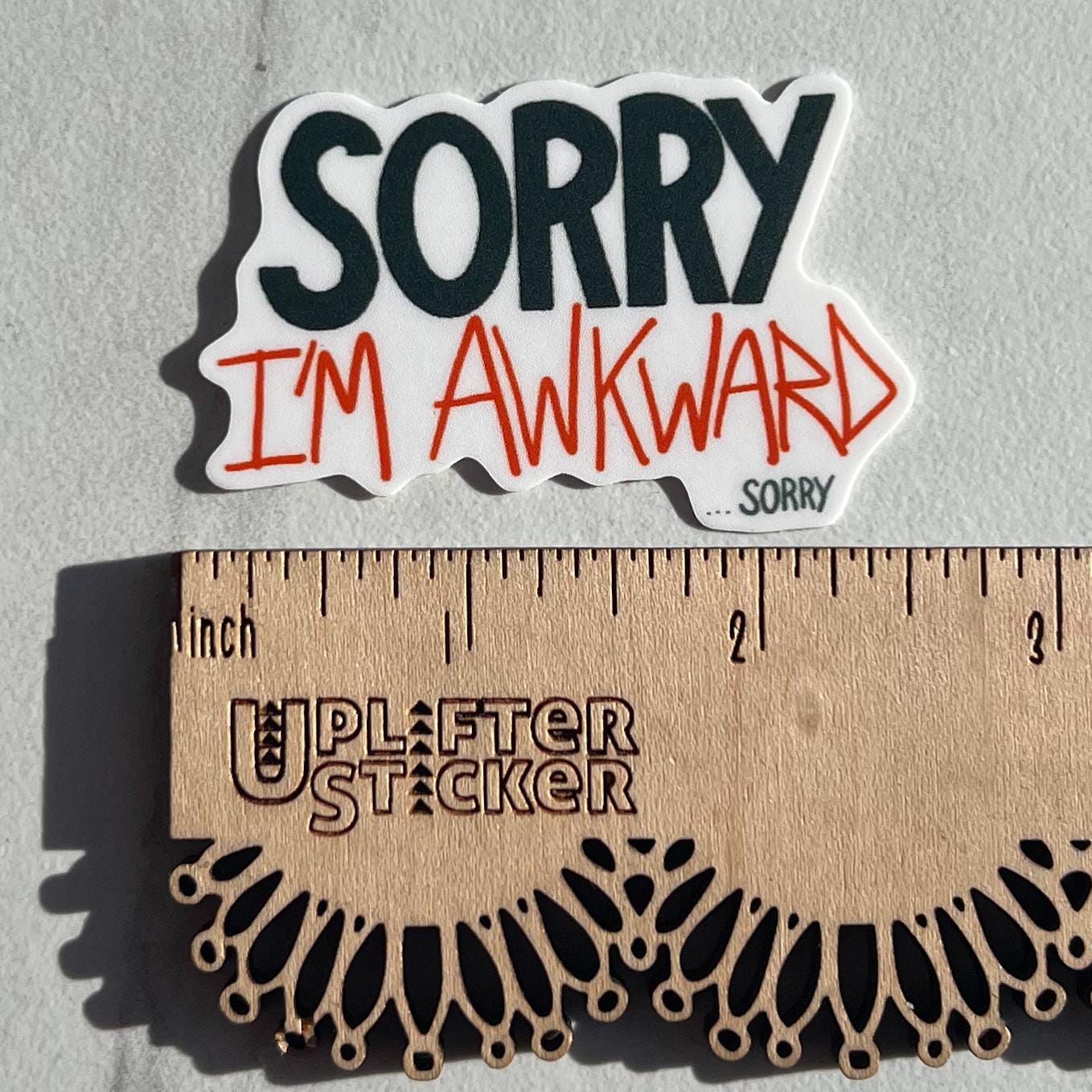 Sticker with 'Sorry I'm Awkward' text next to a ruler for size reference