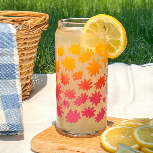 Glass with floral pattern and lemon slice on a wooden board outdoors