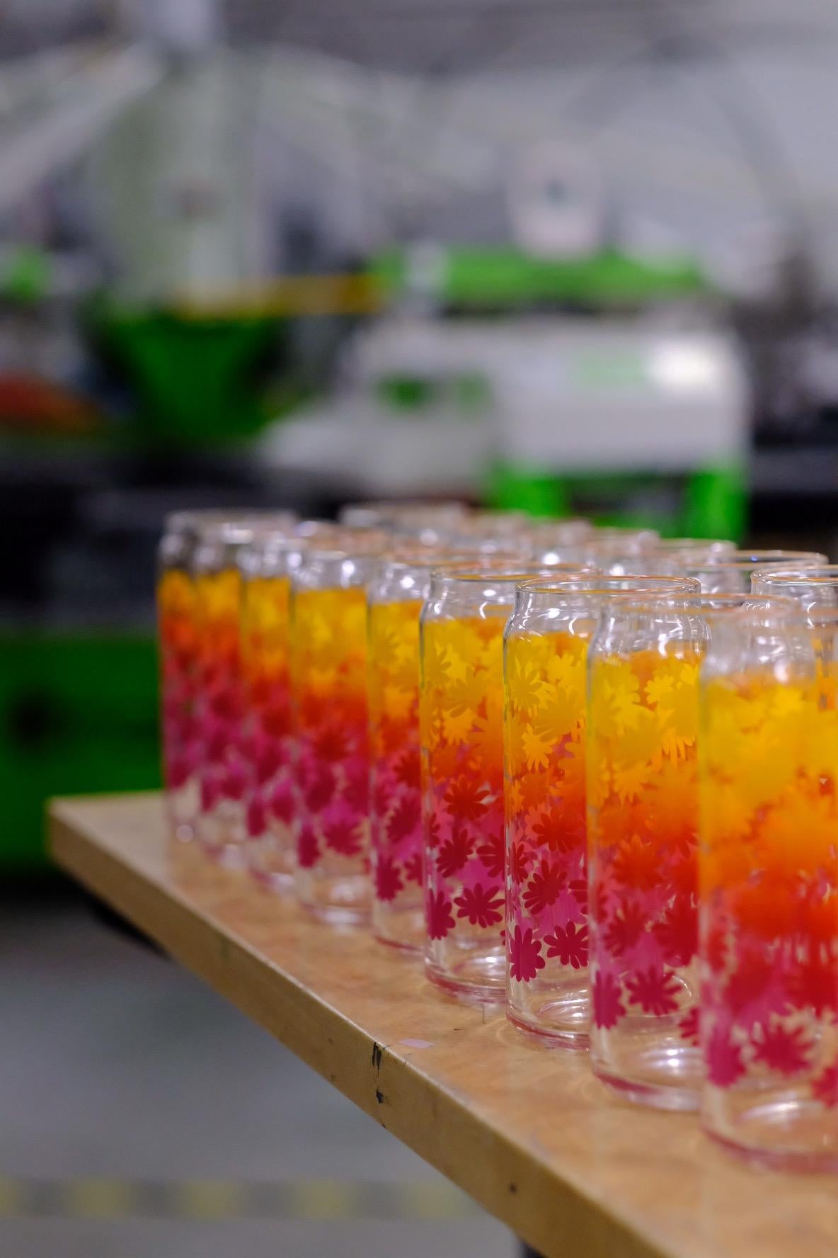 Row of colorful glasses on a wooden surface with a blurred background