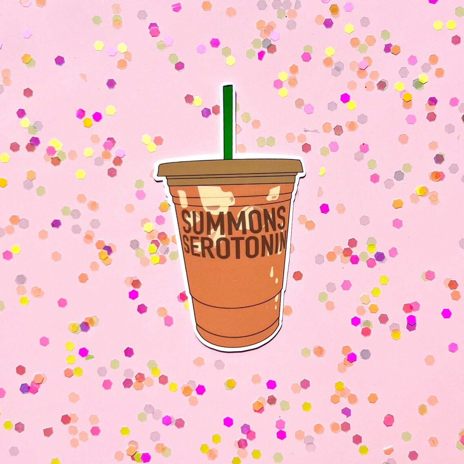 Illustration of a coffee cup with 'SUMMONS SEROTONIN' text on a pink background with colorful confetti.