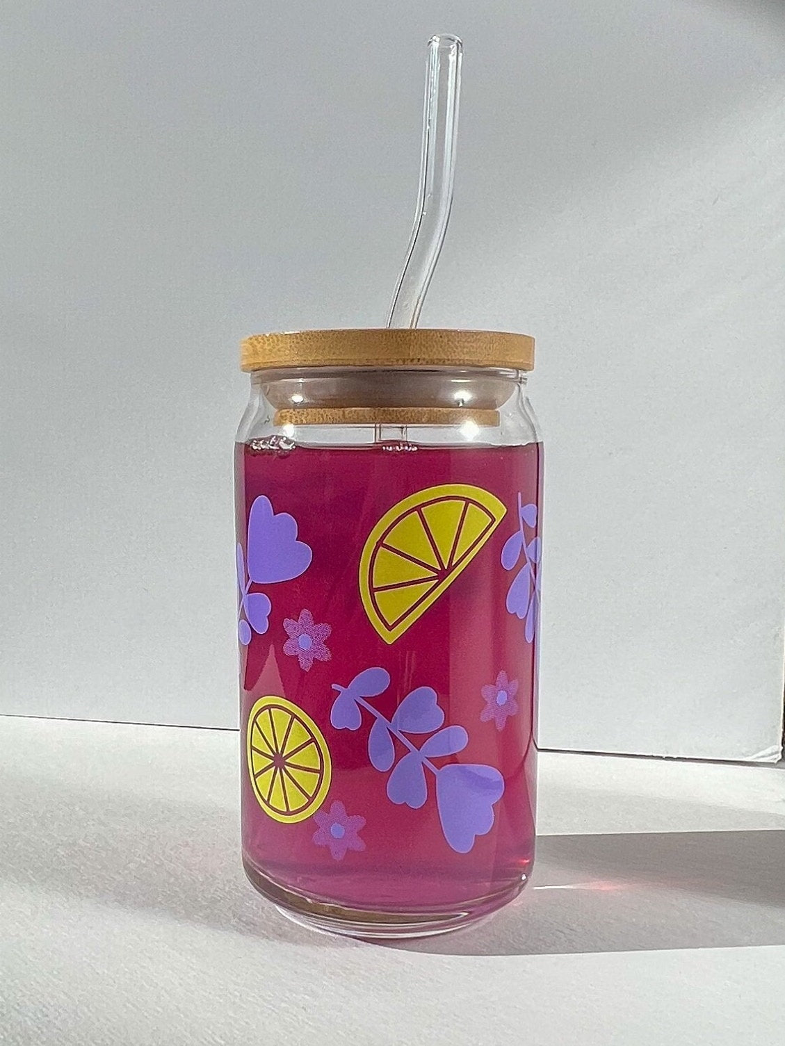 Clear glass can with purple lavender and yellow lemon designs on a white background